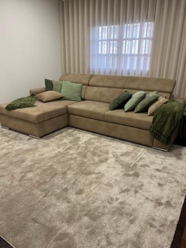 a brown couch with pillows in a living room at Casa São Domingos in Lousada