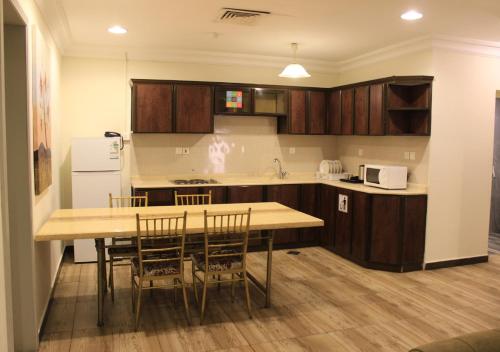 a kitchen with wooden cabinets and a table and chairs at Sea Club Resort in Dammam