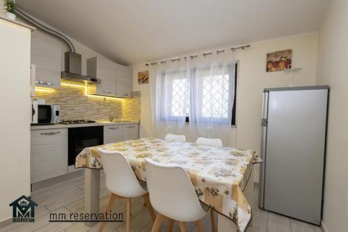 a kitchen with a table with chairs and a refrigerator at Le Ghiande Appartamento Roma in Infernetto