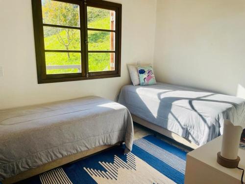 a bedroom with two beds and a window at Casa Aurora, São Francisco Xavier SP in São José dos Campos