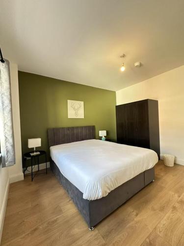 a bedroom with a large bed and a green wall at Abbey Apartments in Dublin