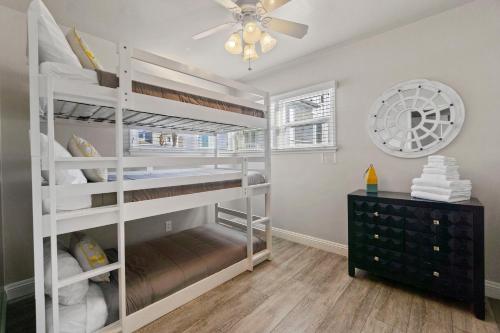 a bedroom with white bunk beds and a ceiling fan at 118 Emerald Ave A & B in Newport Beach