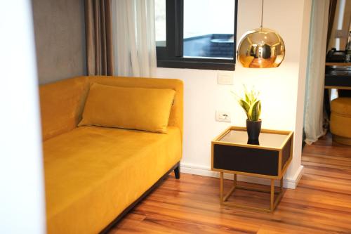 a yellow couch in a living room with a potted plant at La Suite Boutique Hotel in Tirana