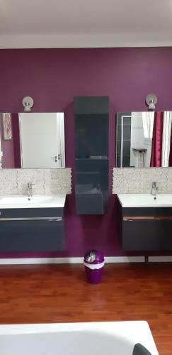La salle de bains est pourvue de 2 lavabos et d'un mur violet. dans l'établissement Le brin de soleil reposant, à Saint-Maurice-lʼExil