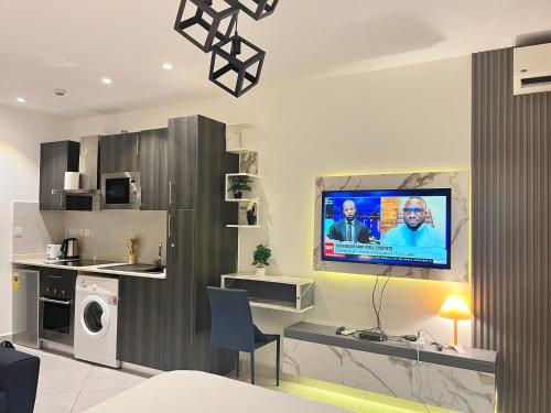 a living room with a tv on a wall at Embassy Gardens Royal Suites Apartments in Accra