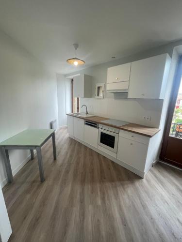 une cuisine avec des armoires blanches et une table à l'intérieur dans l'établissement Appartement Ronzier Joly, à Clermont-lʼHérault