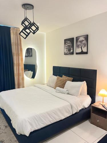 a bedroom with a large bed with white sheets at Embassy Gardens Royal Suites Apartments in Accra