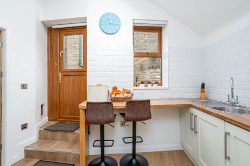 a kitchen with a counter and two stools at Kinder Apartment Central Glossop in Glossop