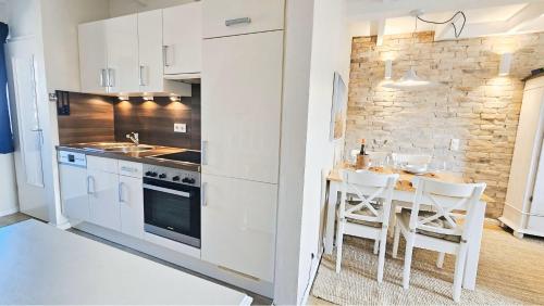 a kitchen with white cabinets and a table with chairs at Lazy Osyter Sylt in Braderup