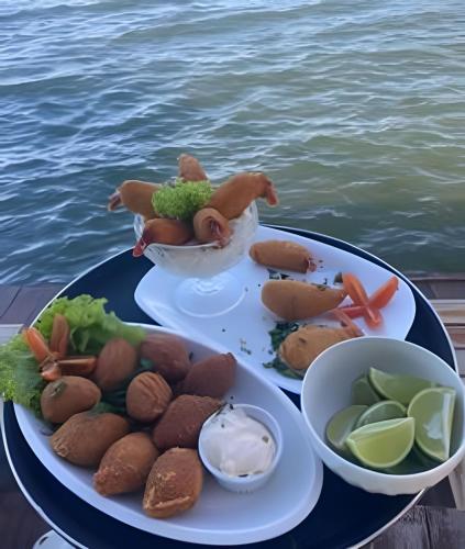 a table with a plate of food next to the water at Pousada Cocobeach Adventure - Miracema do Tocantins in Palmas