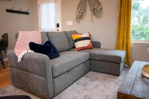 a living room with a gray couch with colorful pillows at Upper Mountain Haus Studio Close to Slopes Mtns in Ogden