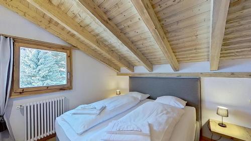 una camera da letto con un grande letto bianco con una finestra di Abitaziun Prünella - La Punt Chamues-ch a La Punt-Chamues-ch