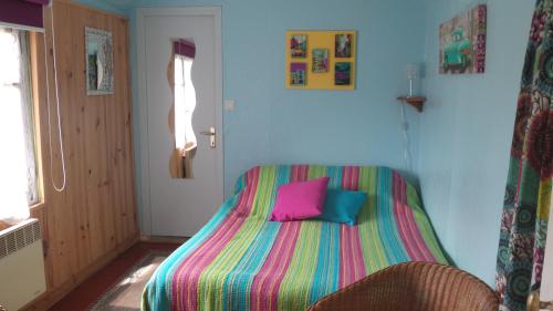 - une chambre dotée d'un lit avec des draps colorés et d'une fenêtre dans l'établissement Gite Les Oiseaux, au Tréport