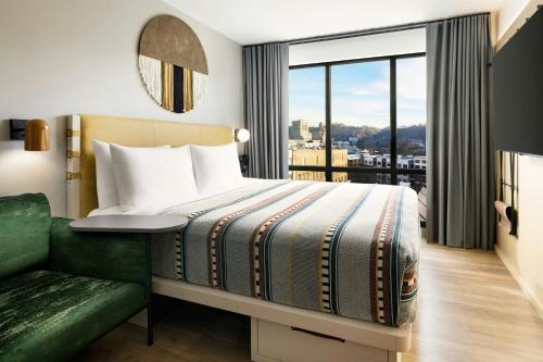a hotel room with a bed and a green couch at Moxy Asheville in Asheville