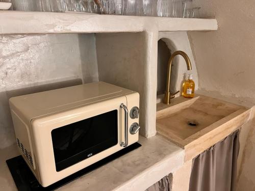 un four micro-ondes assis sur un comptoir à côté d'un évier dans l'établissement Les Caves d 'Oía, à Aix-en-Provence