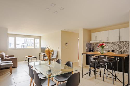 a kitchen and living room with a glass table and chairs at Gray Fox Apartments - San Martin in Ushuaia
