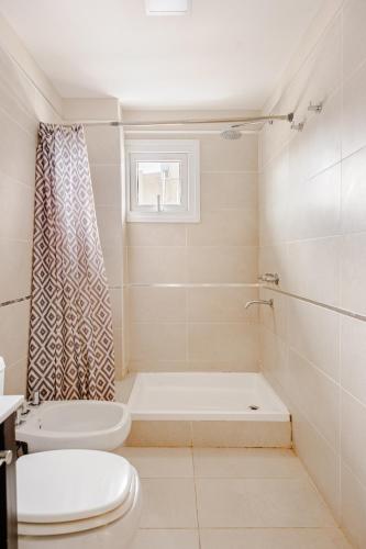 a white bathroom with a toilet and a shower at Gray Fox Apartments - San Martin in Ushuaia