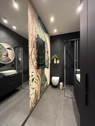 a bathroom with a wall with a tree mural at Apartament Pod Żaglami 2 in Sława