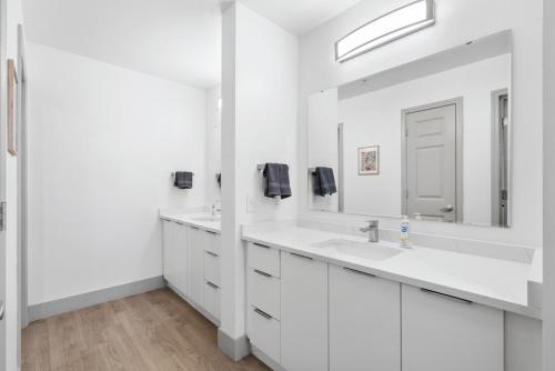 a white bathroom with two sinks and a mirror at Uptown Luxury - Top Floor King Suite, Free Parking in Charlotte