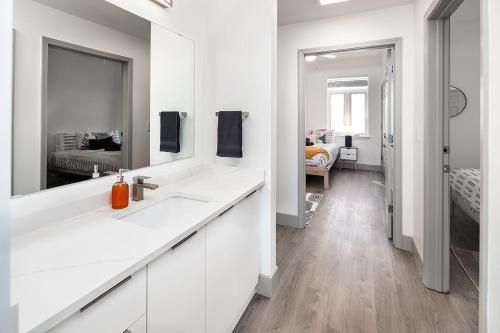 a white bathroom with a sink and a mirror at Urban Retreat - Free Parking, WiFi, Walk to Stadium in Charlotte
