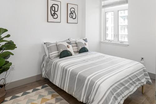 a white bedroom with a bed with a striped blanket at Urban Retreat - Free Parking, WiFi, Walk to Stadium in Charlotte