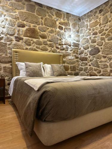 a bed in a room with a stone wall at Alojamento Central in Chaves