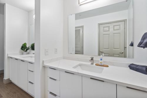 a white bathroom with two sinks and a large mirror at Queen City Retreat - Parking, Views, Near Stadium in Charlotte