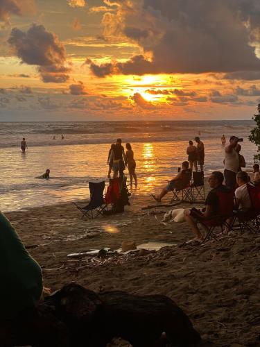 a group of people on the beach at sunset at Cabañas MOHE’S Uvita in Uvita