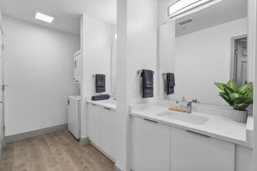 a white bathroom with two sinks and a mirror at Cozy City Charm - Spacious, Parking, Balcony, Gym in Charlotte
