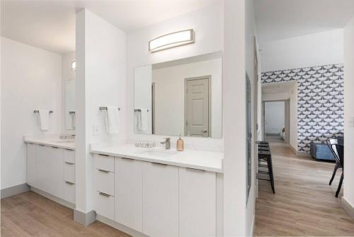 a white bathroom with two sinks and a mirror at The Tar Heel - Stylish 4BR with City Views - Free Parking - Gym in Charlotte