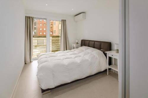 a white bedroom with a large bed and a window at Stormvogel 0102 P15 in Sint-Idesbald