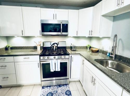 a kitchen with white cabinets and a stove and a sink at Relax & Unwind in 2BR 1BA Home in Quiet Neighborhood in Nederland