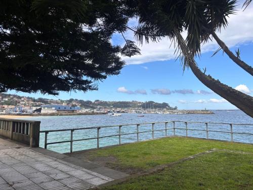 a view of the ocean with a bench and a fence at Duplex Bueu Vistas con terraza in Bueu