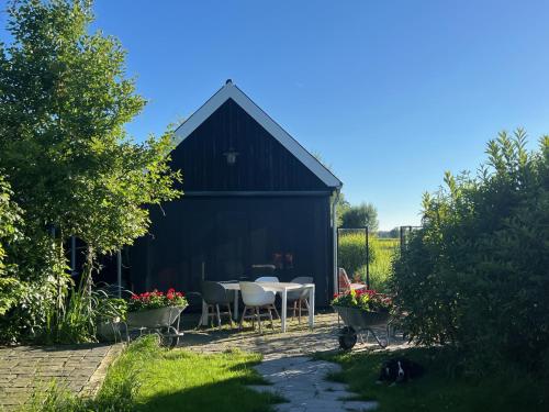 a black barn with a table and chairs in a yard at Weg-van-de-stad vakantieverblijf in 't Harde