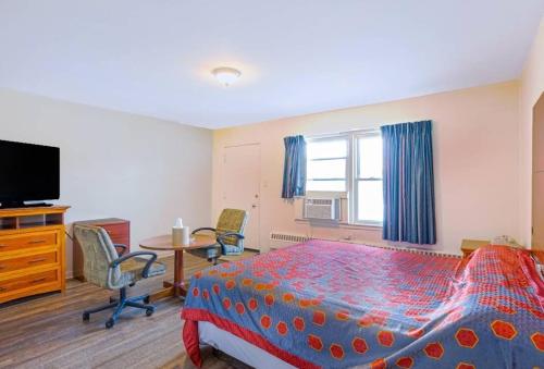 a bedroom with a bed and a tv and a table at Hillside Manor Motel in Hillside