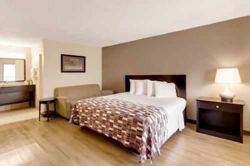 a hotel room with a bed and a chair at Red Roof Inn Gulfport - Biloxi Airport in Gulfport