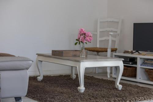 a white coffee table with a vase of flowers on it at Le repere du forestier in Sabres
