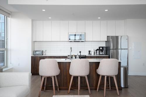 a kitchen with three bar stools and a refrigerator at Ultra Luxury Apt - Panoramic NYC View - Minutes to City in Hoboken