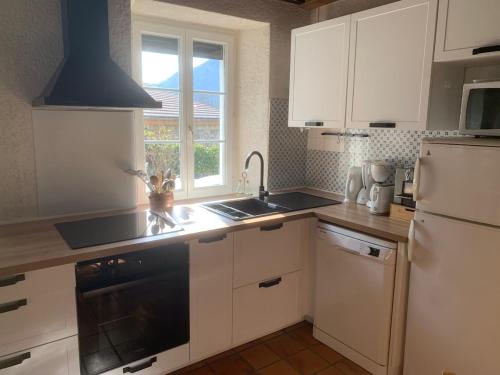 une cuisine avec des armoires blanches, un évier et un réfrigérateur dans l'établissement Maison au calme avec vue sur montagne, à Ornolac-Ussat-les-Bains