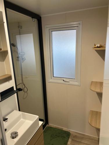 une salle de bain avec une douche et un lavabo et une fenêtre dans l'établissement Mobil home SFI, à Canet