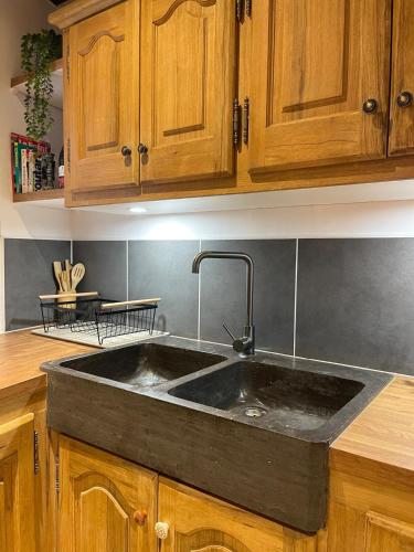 - une cuisine avec un évier noir et des placards en bois dans l'établissement Maison de charme, à Apt