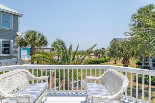 a balcony with two wicker chairs and palm trees at Charleston Charm - Pool & Ocean Views in Cedar Reef Villas