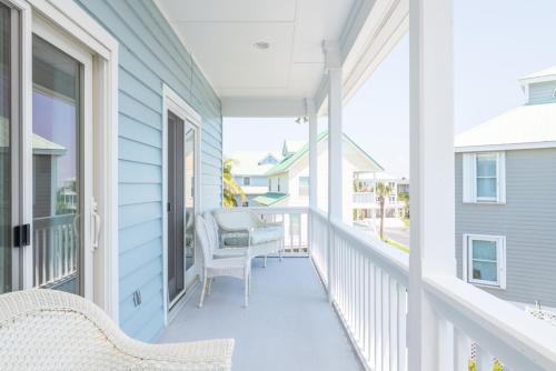 a porch with two wicker chairs on a blue house at Charleston Charm - Pool & Ocean Views in Cedar Reef Villas
