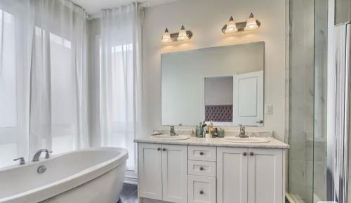 a bathroom with two sinks and a tub and a mirror at XTO Hotel in Markham