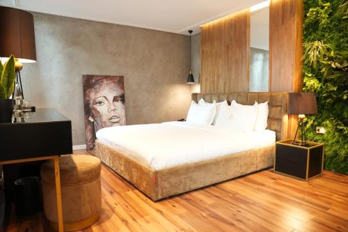 a bedroom with a bed with a painting on the wall at La Suite Boutique Hotel in Tirana
