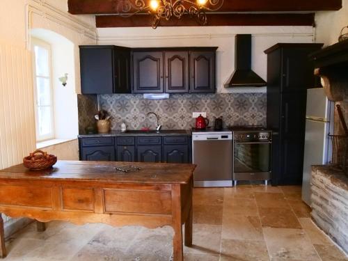 une cuisine avec des armoires noires et une table en bois dans l'établissement Maison Les Sauvages Blassac 8-10 personnes, à Blassac