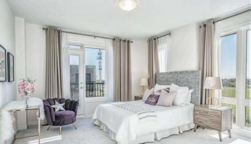 a bedroom with a bed and a chair and windows at XTO Hotel in Markham