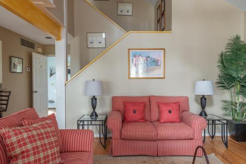 a living room with two red chairs and a staircase at Quiet Dataw Island Villa with Water Views in Dataw Island