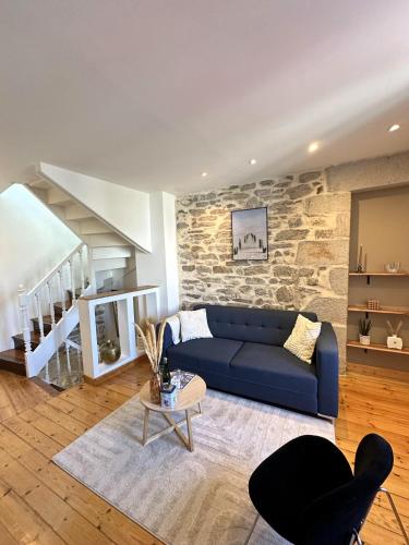 - un salon avec un canapé bleu et un mur en pierre dans l'établissement Maison de charme Locmaria, à Quimper