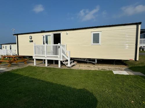 a large yellow house with a porch and a deck at Modern Caravan 2 Bedrooms Sleeps 6 near Weymouth in Wyke Regis